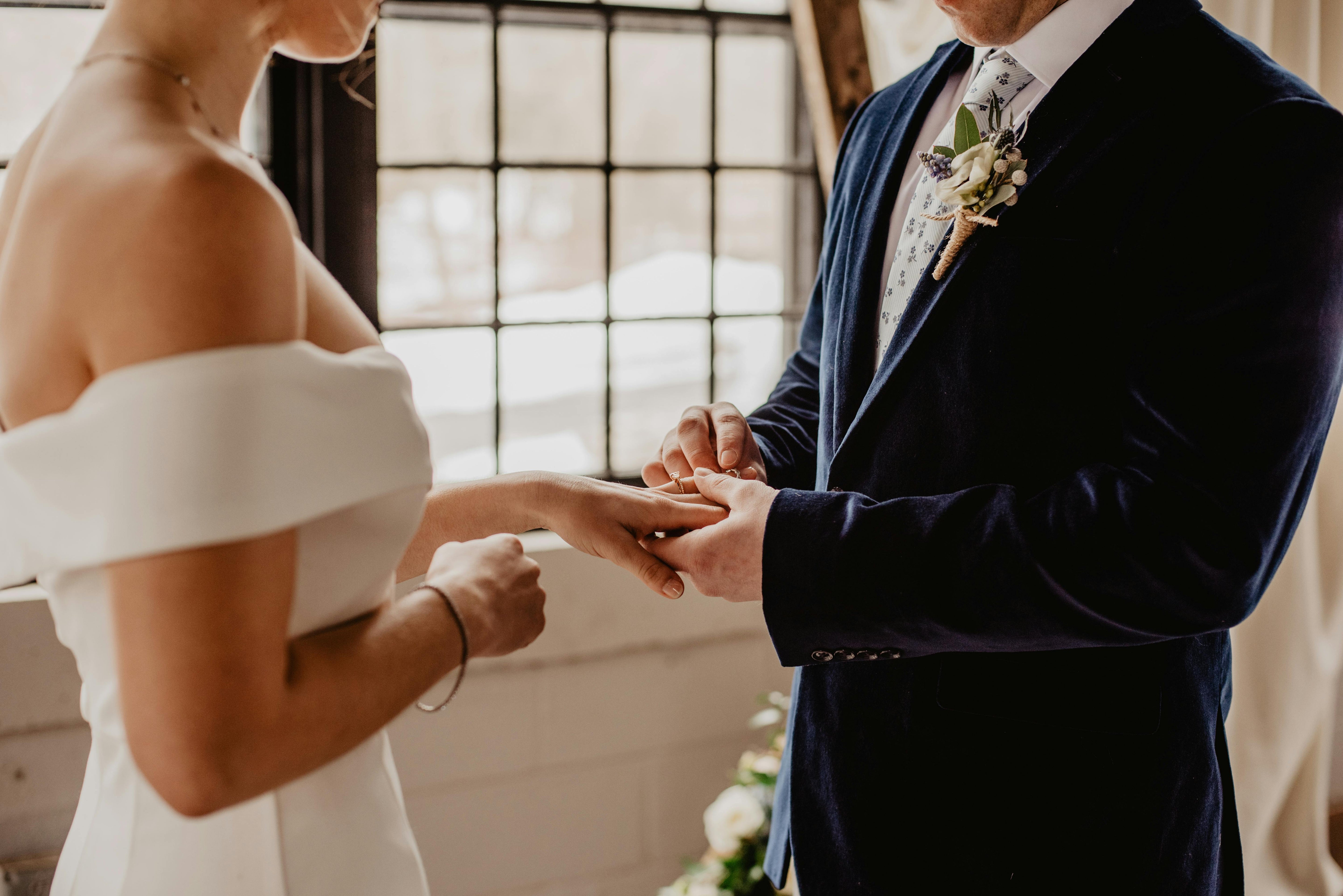 groom puts a ring on brides finger